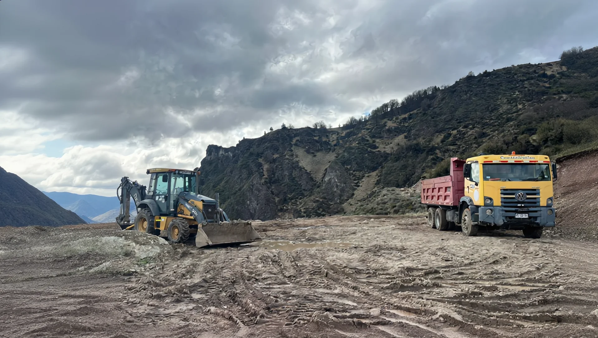 Retroexcavadora y camión tolva trabajando juntos en faena de Aysén